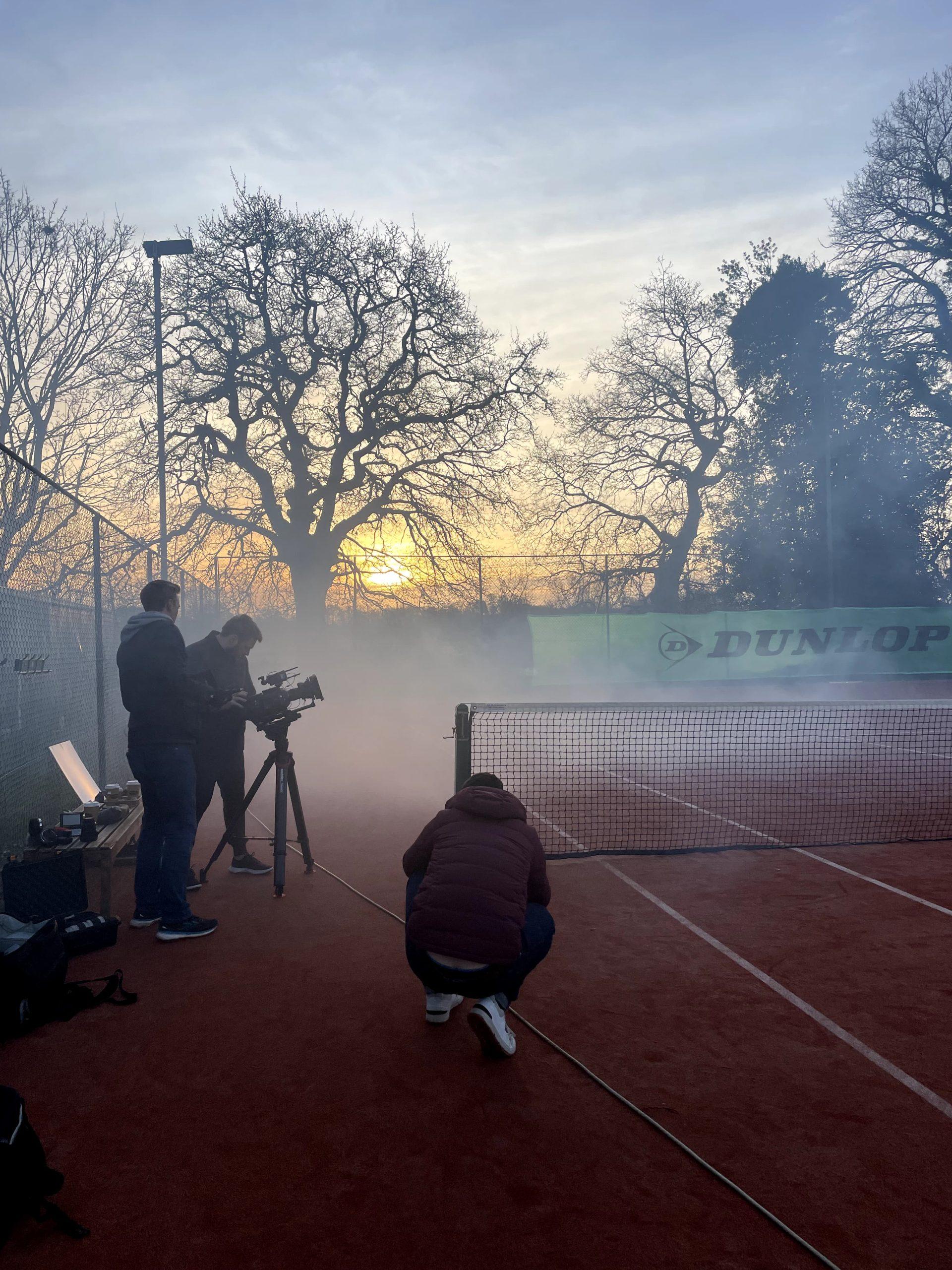 Team members from Orangery, content creation agency, videoing on a tennis court in sunrise.